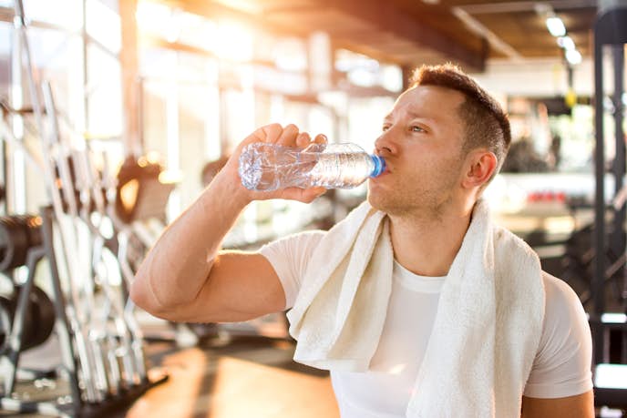 筋トレの効果を上げるために水を飲んでいる男性