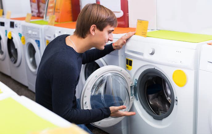 乾燥機付き洗濯機の中身を見る男の人