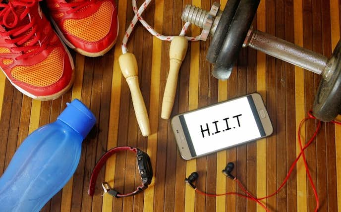 HIITトレーニングが表示されたスマホとトレーニング器具